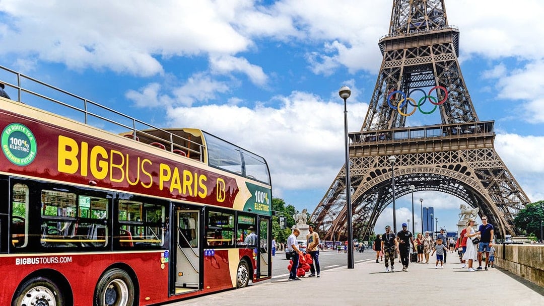 Big Bus Paris tour near Eiffel Tower with Olympic rings, Paris, France.