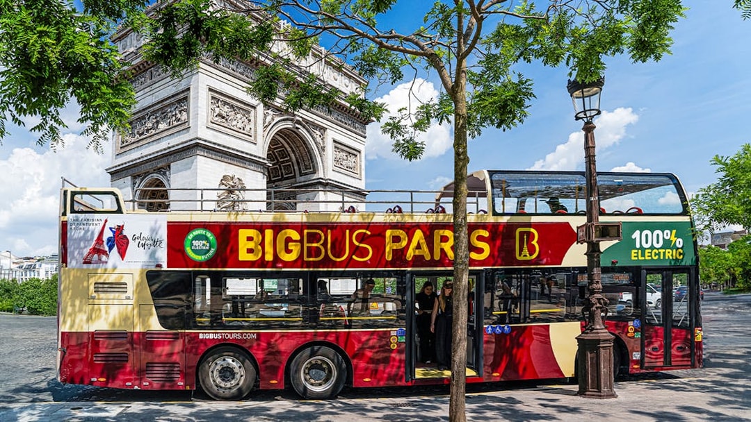 Big Bus Paris tour near Arc de Triomphe, featuring an electric double-decker bus.
