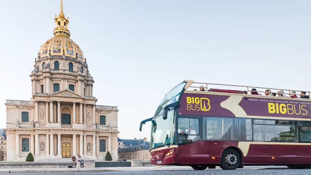 Big Bus Paris tour passing Les Invalides with tourists on board.