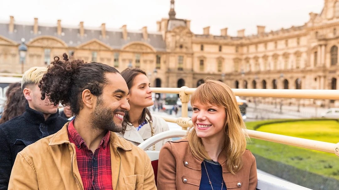 Tourists enjoying a Paris hop-on hop-off bus tour near Place Vendôme.