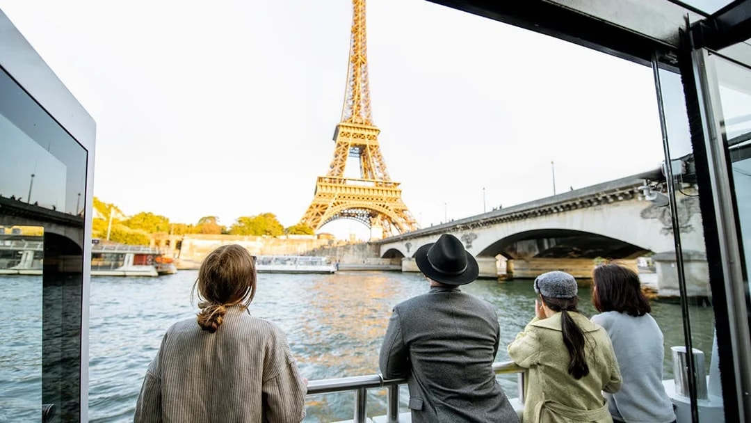 Tourists on Seine River Cruise viewing Eiffel Tower in Paris.