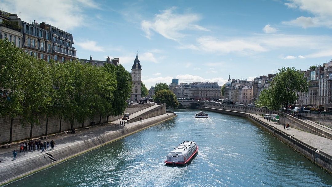 Seine River cruise boat passing under a bridge in Paris with cityscape views.