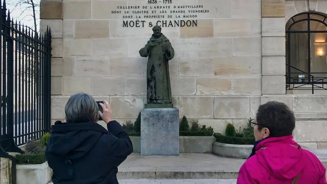 Visitors photographing Dom Perignon statue at Moët & Chandon, Champagne region tour.