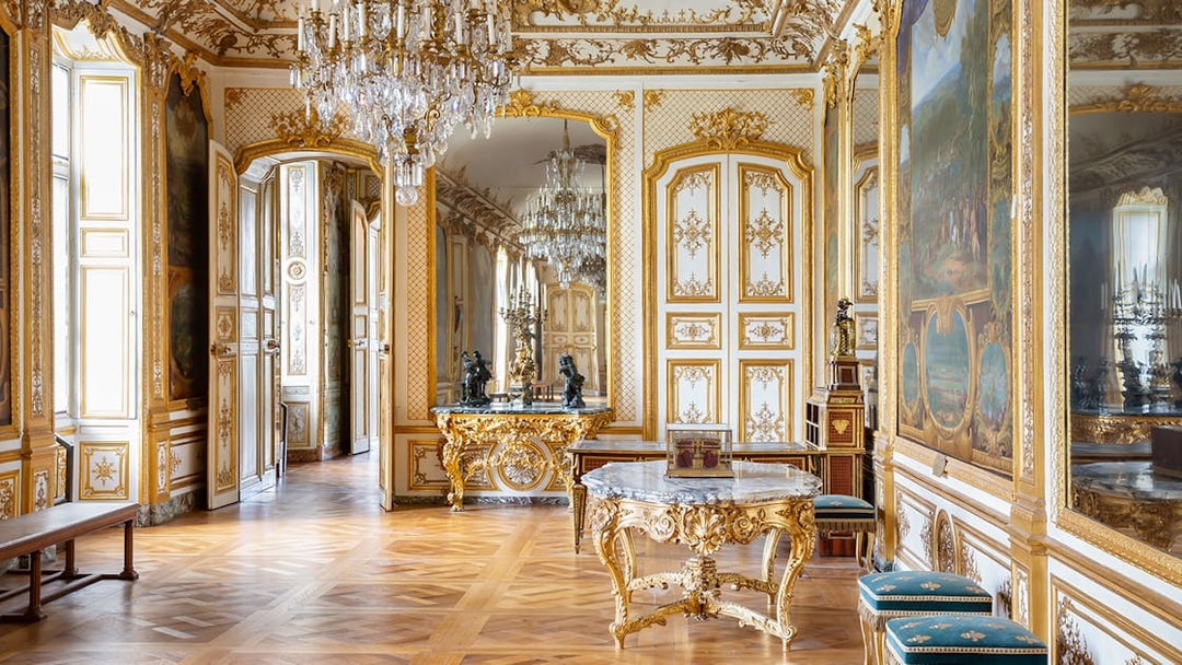 Chateau of Chantilly ornate room with gilded decor and chandeliers.