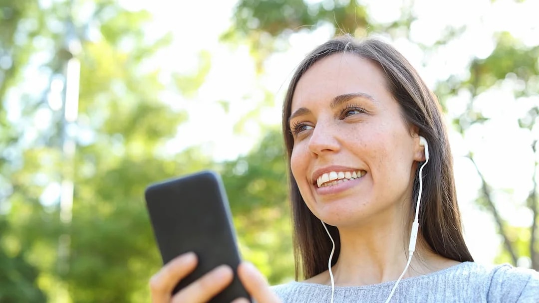 Woman listening to audioguide on phone during Château of Chantilly tour.