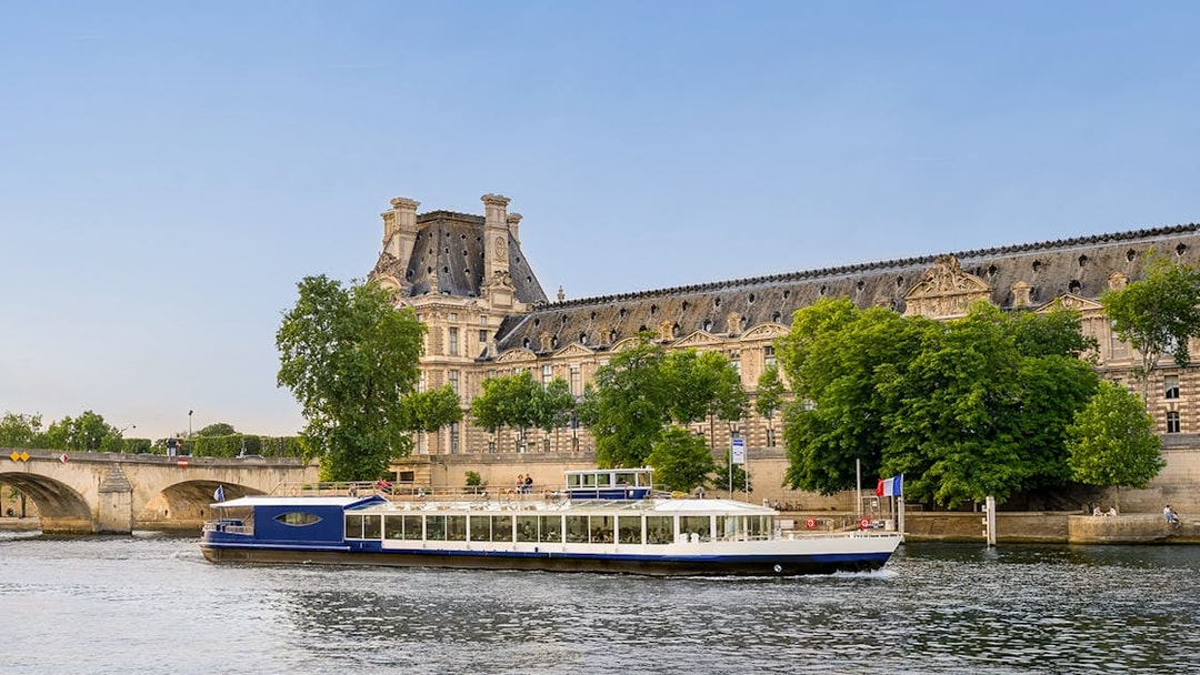 Dinner cruise boat on the Seine River passing by the Louvre Museum in Paris.