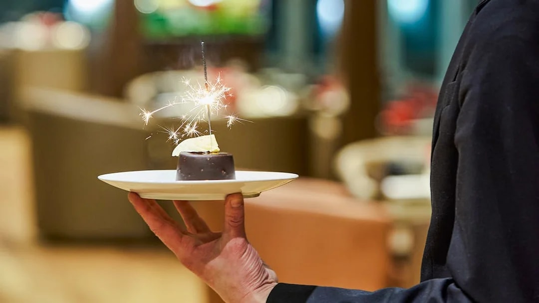 Waiter serving dessert with sparkler on Paris En Scène Dinner Cruise, Seine River.