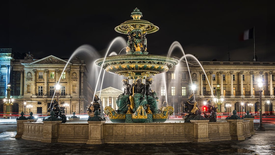 Fountain at Place de la Concorde in Paris at night with illuminated buildings.