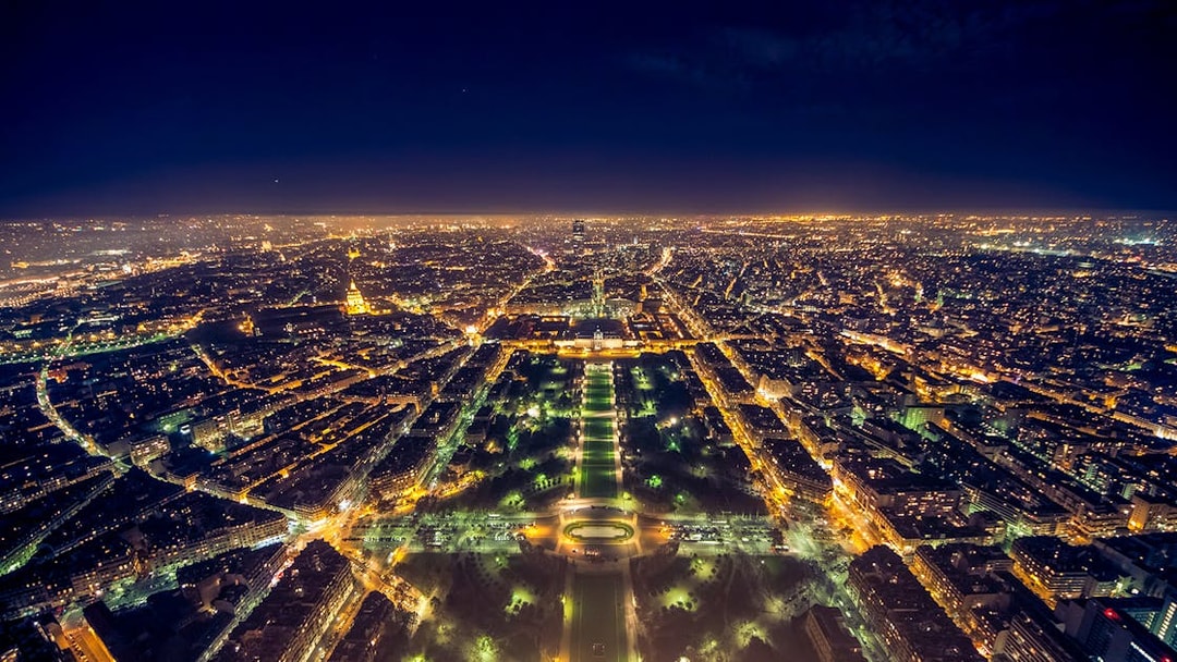 View from the Eiffel Tower summit overlooking Paris city lights at night.