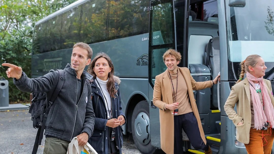 Visitors disembarking a bus on a guided tour from Paris to Mont Saint-Michel.