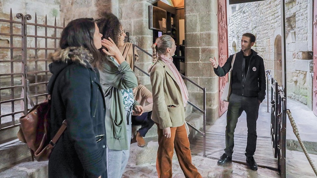 Visitors listening to a guide at Mont Saint-Michel entrance.