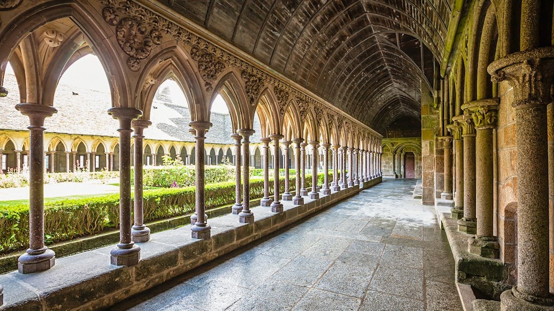 Cloister arches at Mont Saint-Michel, France, with garden view.
