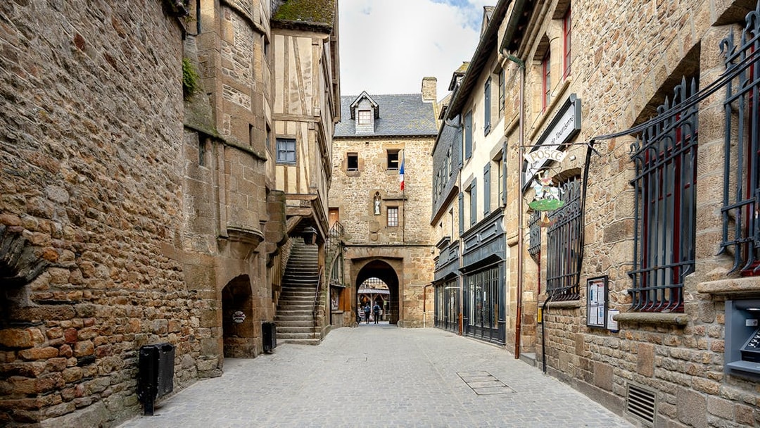 Mont Saint-Michel stone street with historic buildings and archway, France.