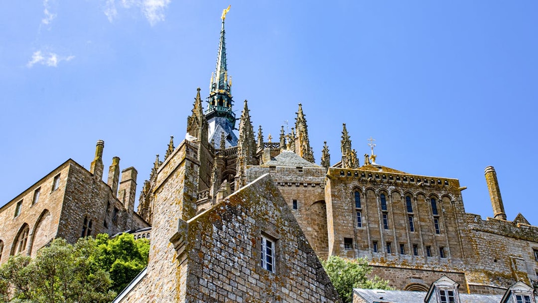 Mont Saint Michel abbey spire and stone architecture under blue sky, Normandy, France.