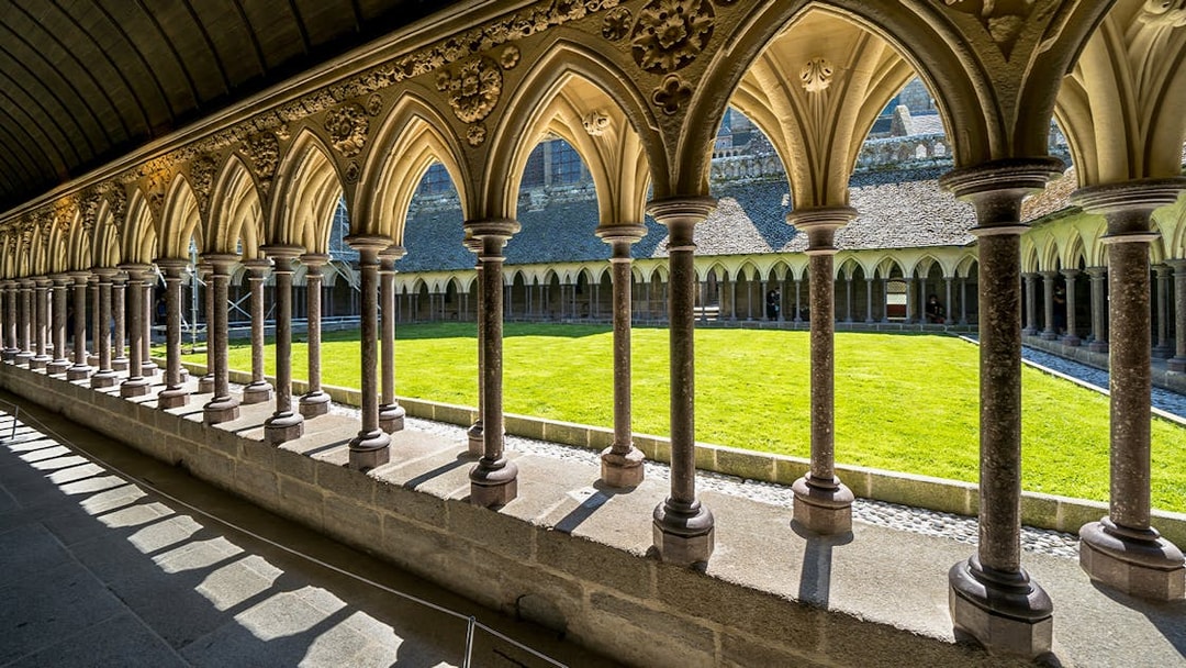Cloister arches at Mont St. Michel with view of the courtyard lawn.