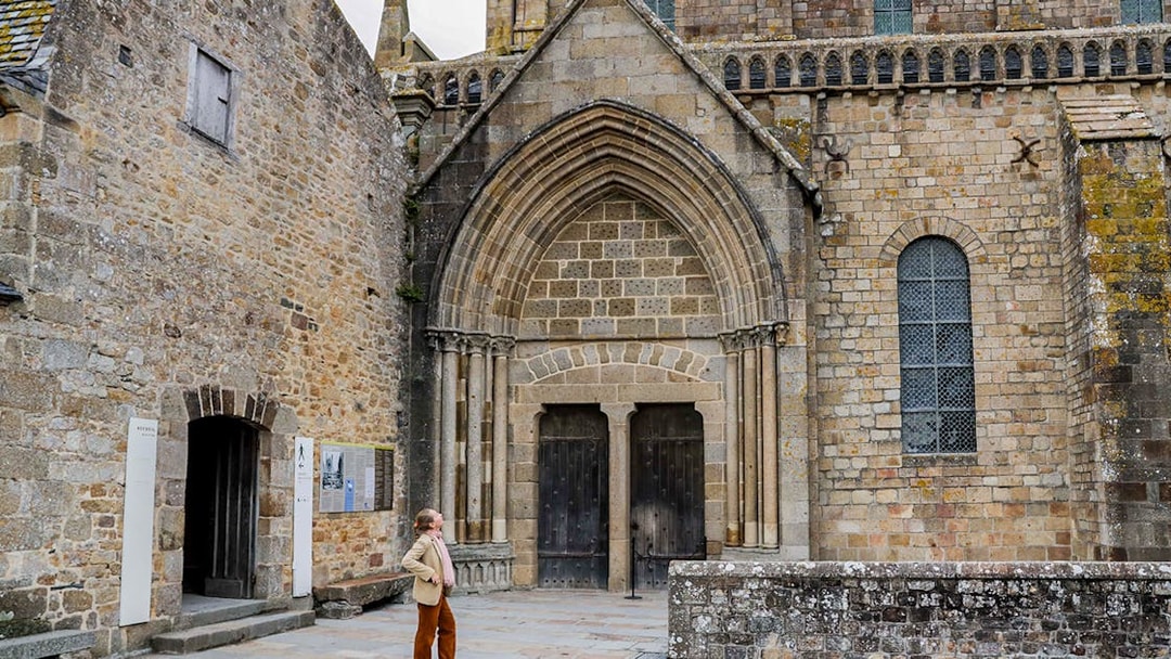 Tourist exploring Mont St. Michel Abbey's historic entrance on a full-day tour from Paris.