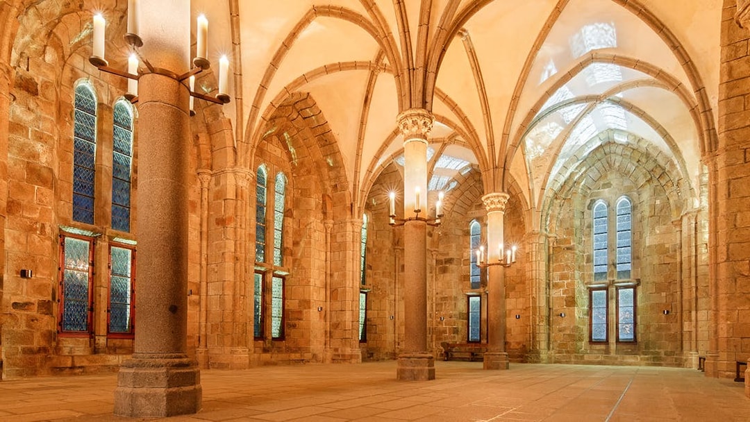 Mont St. Michel Abbey interior with vaulted ceilings and candlelit columns.
