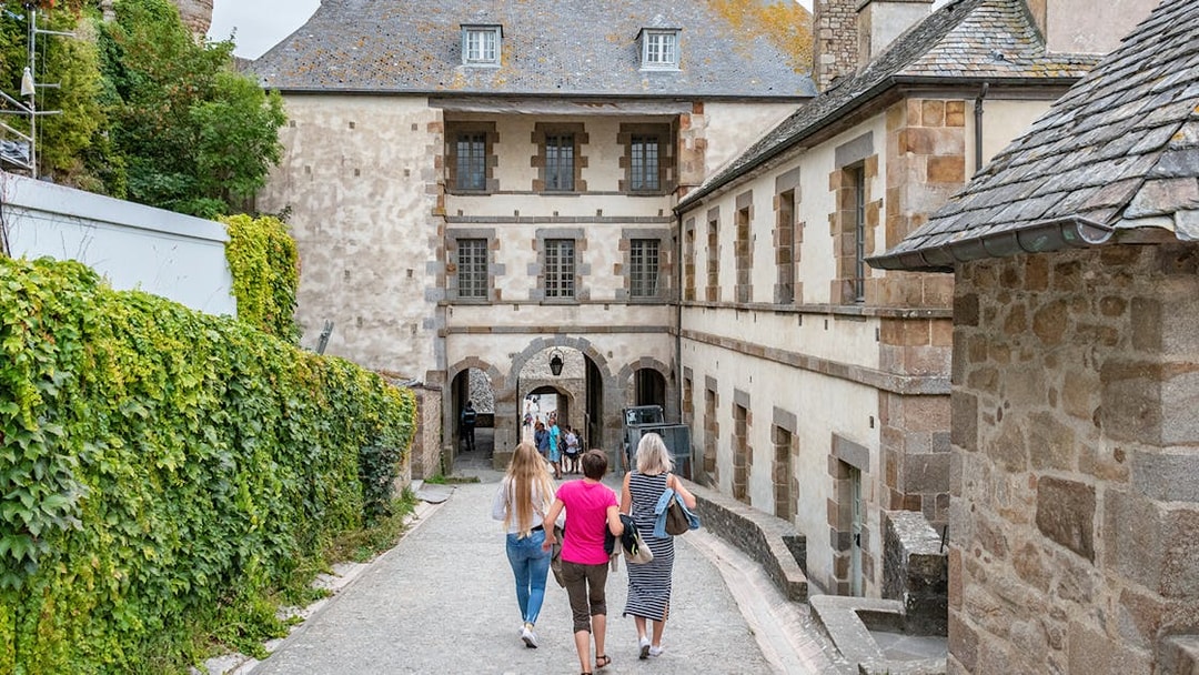 Visitors walking through Mont Saint-Michel's historic stone archway.