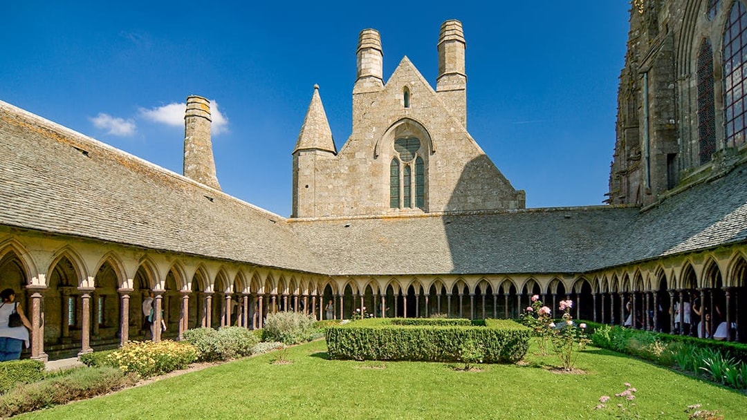 Mont St. Michel Abbey cloister with tourists on a full-day tour from Paris.