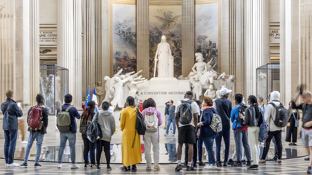 Visitors observing statues inside the Paris Pantheon.