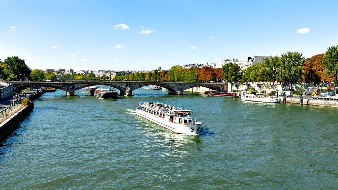 Seine River cruise boat passing under a bridge in Paris.