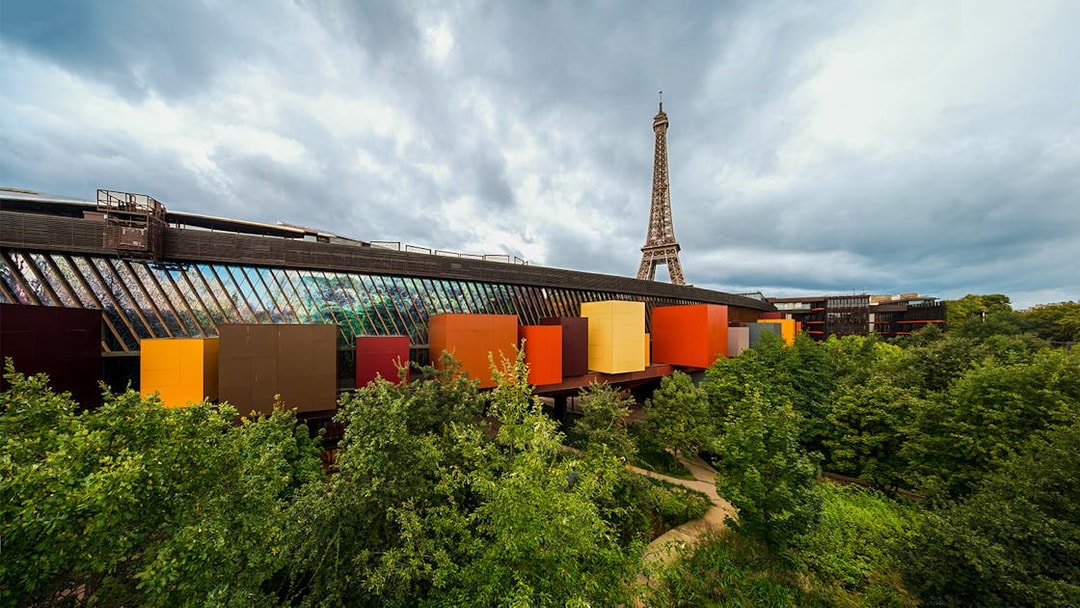 Quai Branly Museum exterior with colorful facade, Eiffel Tower in background, Paris.