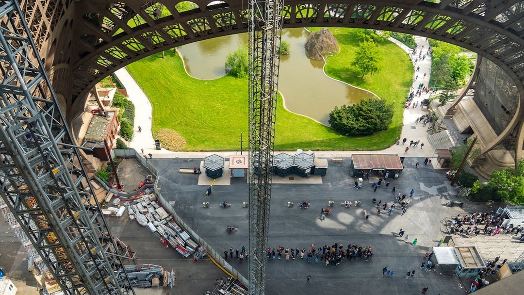 Eiffel Tower view from elevator, showing base structure and surrounding park in Paris.