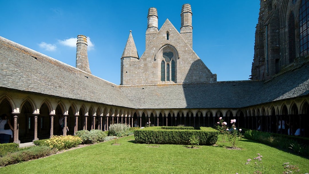 Cloister garden at Mont Saint Michel Abbey, France, under a clear blue sky.