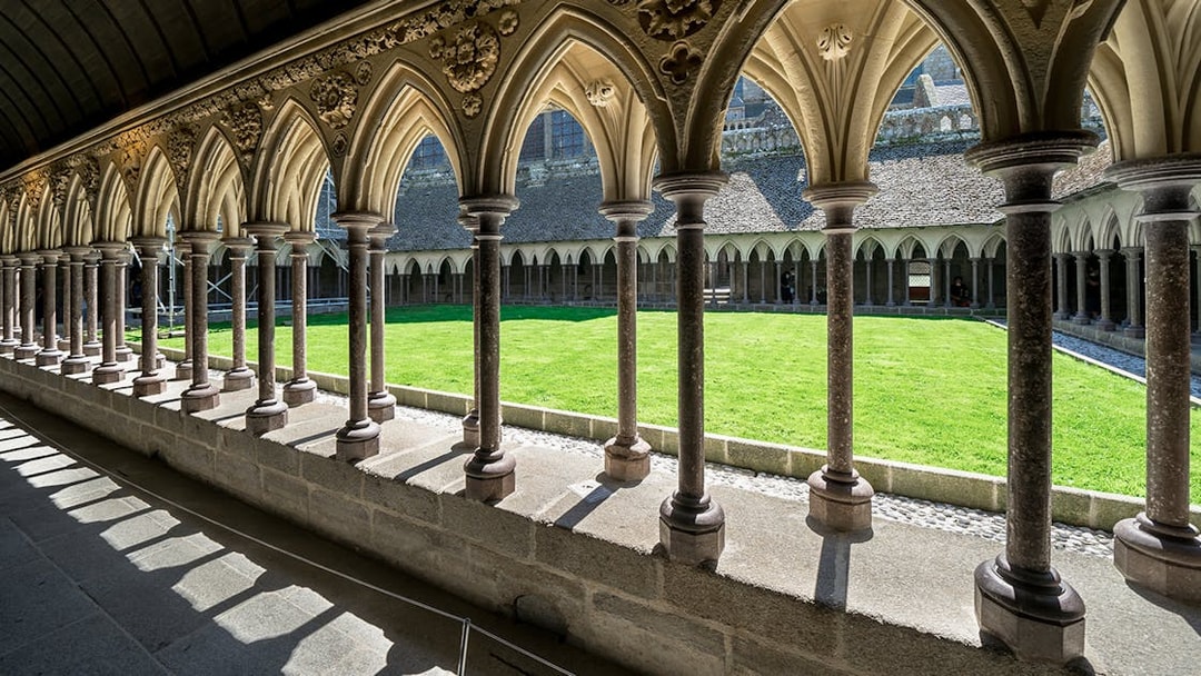 Cloister arches and green courtyard at Mont Saint Michel, France.