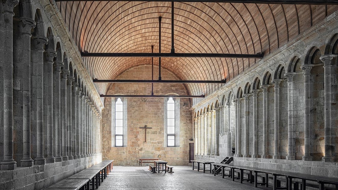 Interior of Mont Saint Michel Abbey with stone columns and arched ceiling.