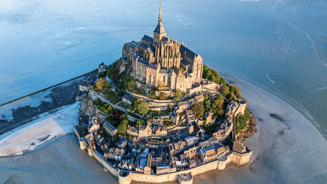 Aerial view of Mont Saint Michel surrounded by water and sand in Normandy, France.