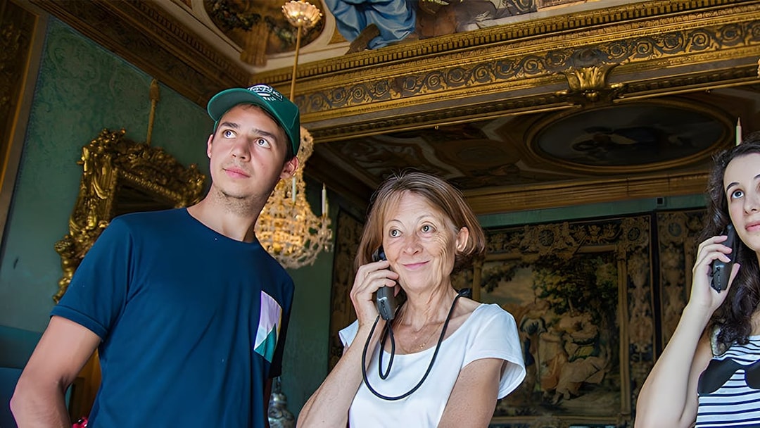 Visitors using audio guides inside Vaux-le-Vicomte, Paris tour.