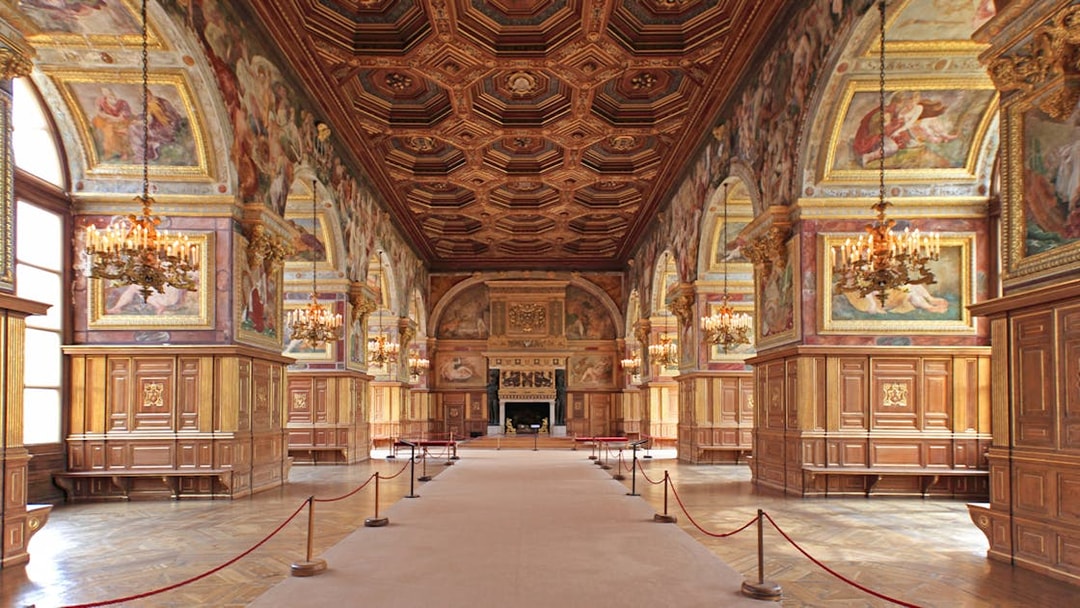 Château de Fontainebleau grand hall with ornate ceiling and chandeliers.