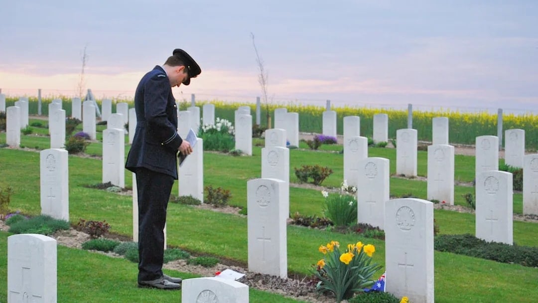 Person in uniform at Somme Battlefields cemetery, France, with rows of white gravestones.