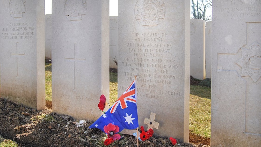 Australian soldier's grave with flag and poppies at Somme battlefield cemetery.