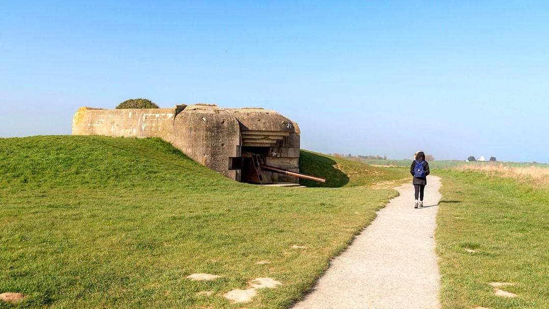 Path leading to a World War II bunker in Normandy, France, with a person walking.