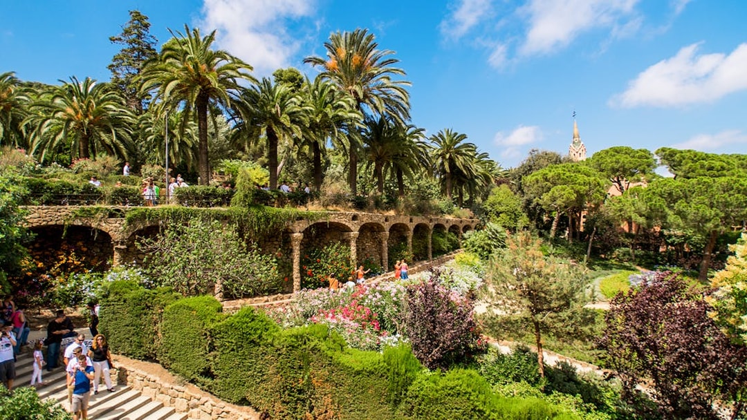 Park Guell's Walk of the Palm Trees with stone arches and lush gardens in Barcelona.