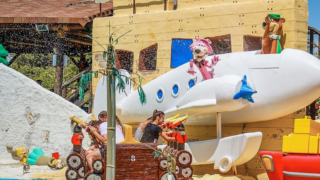 Parque Warner Madrid water ride with cartoon characters and visitors spraying water.