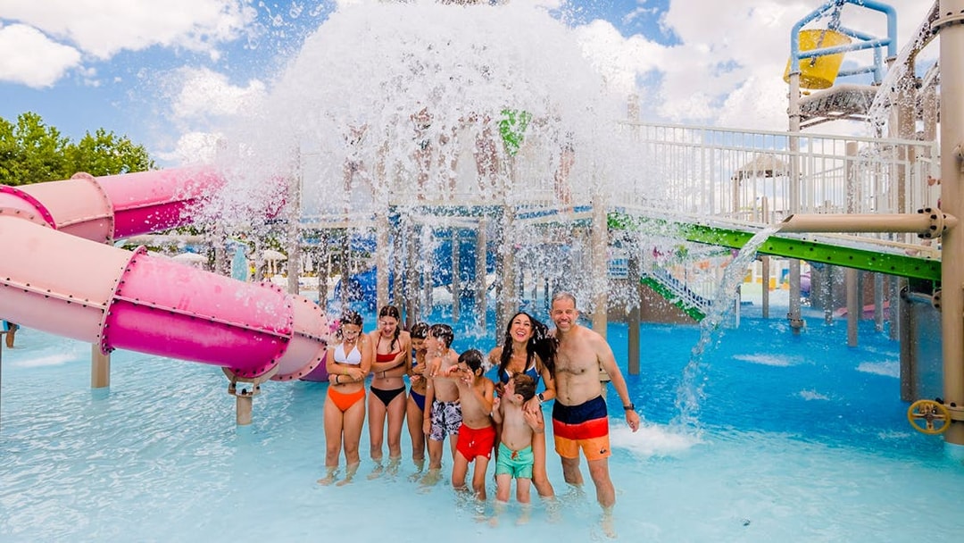 Visitors enjoying water slides and splash area at Parque Warner Beach in Madrid, Spain.