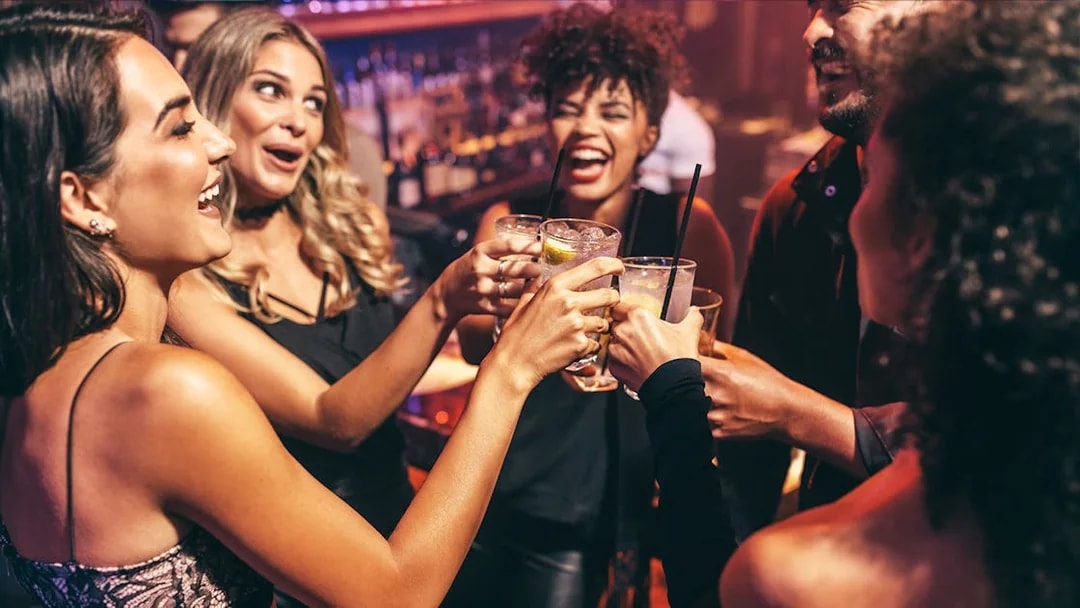 Friends toasting with drinks at a lively club.