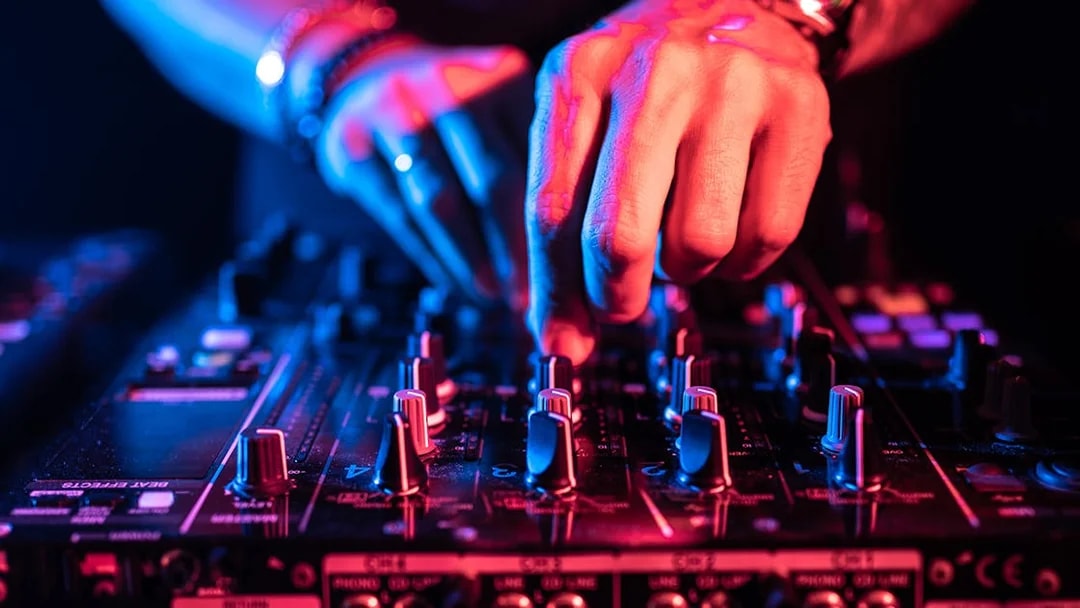 DJ adjusting controls on a music table at a nightclub.