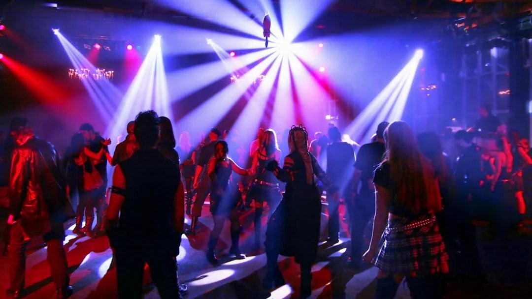 Nightclub crowd dancing under colorful lights.