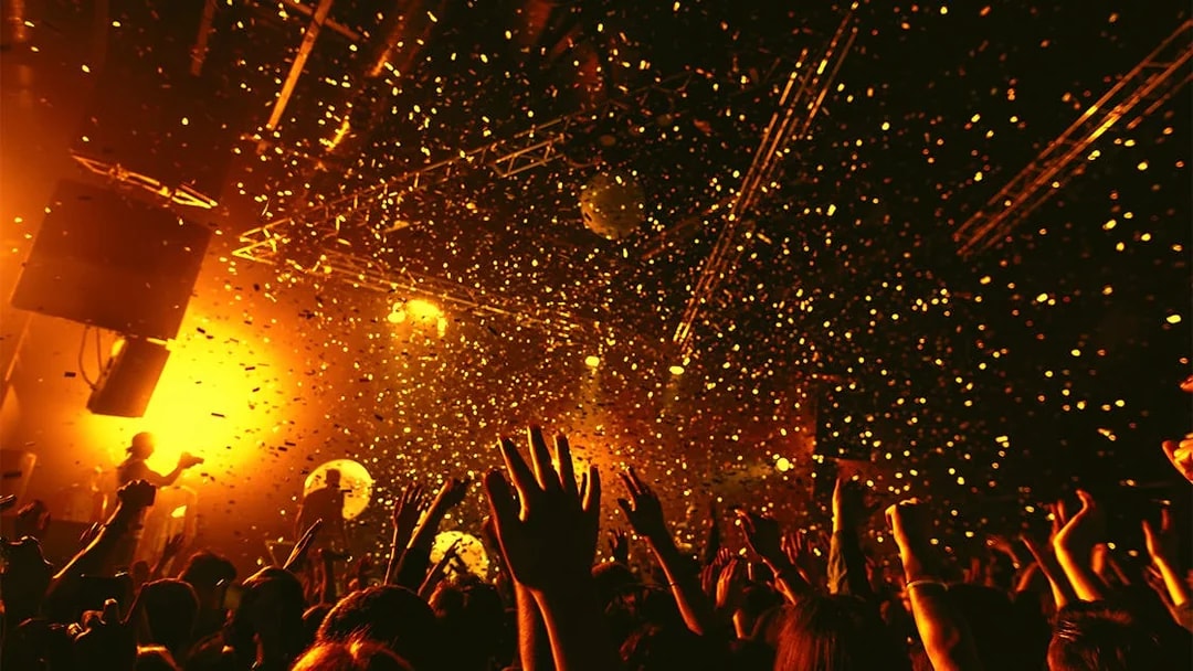 Nightclub crowd dancing under confetti and lights.