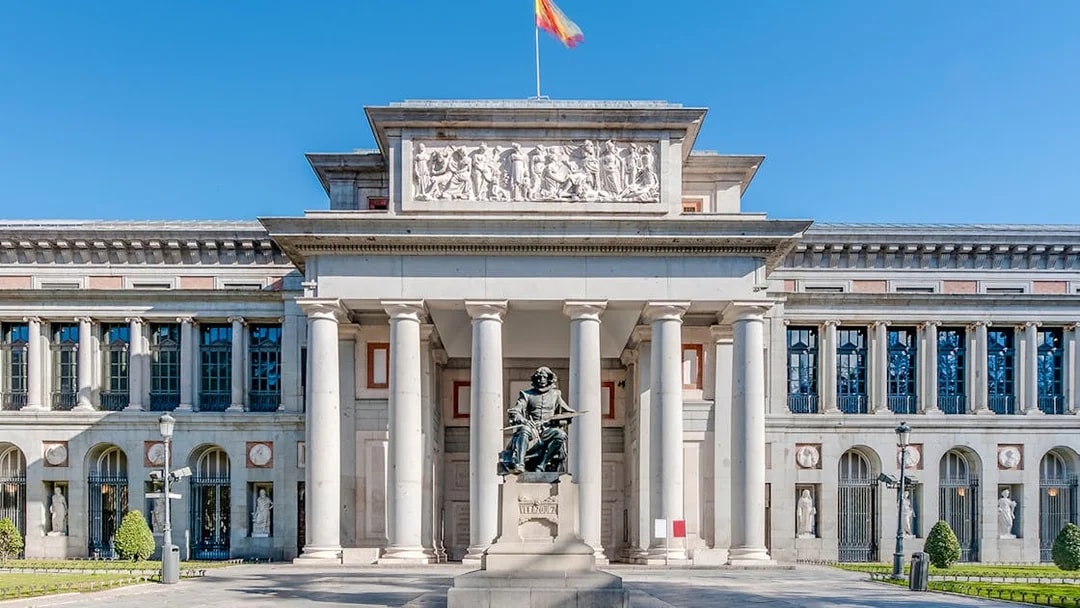 Facade of Prado Museum in Madrid with detailed neoclassical architecture and statue.