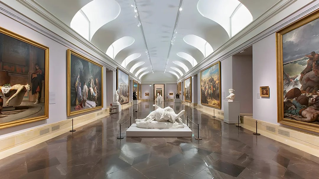 Prado Museum gallery with classical paintings and sculptures on display.