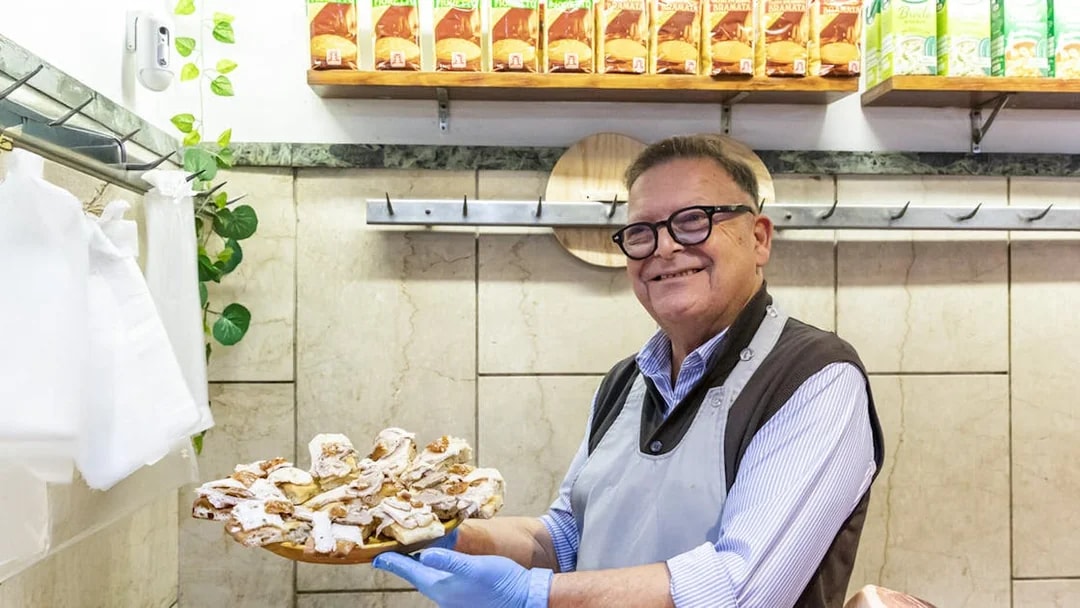 Man in Trastevere shop holding a platter of porchetta slices, Rome.