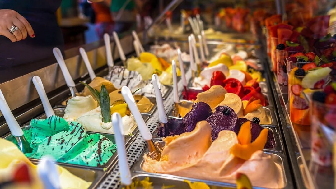 Gelato selection in Florence shop with various flavors and toppings.