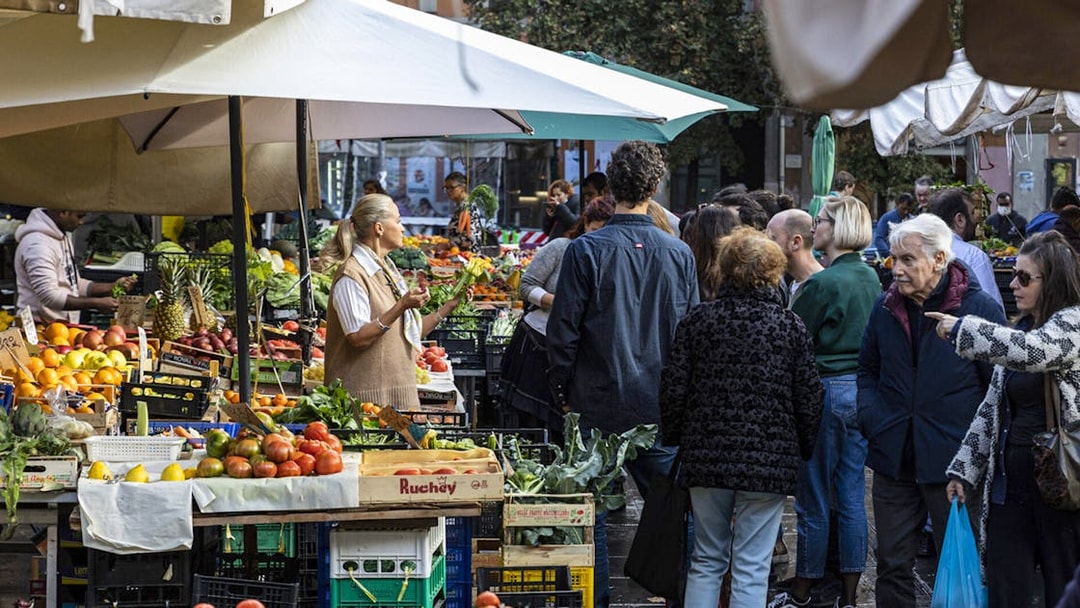 Crowd exploring fresh produce at Rome's San Cosimato Food Market.