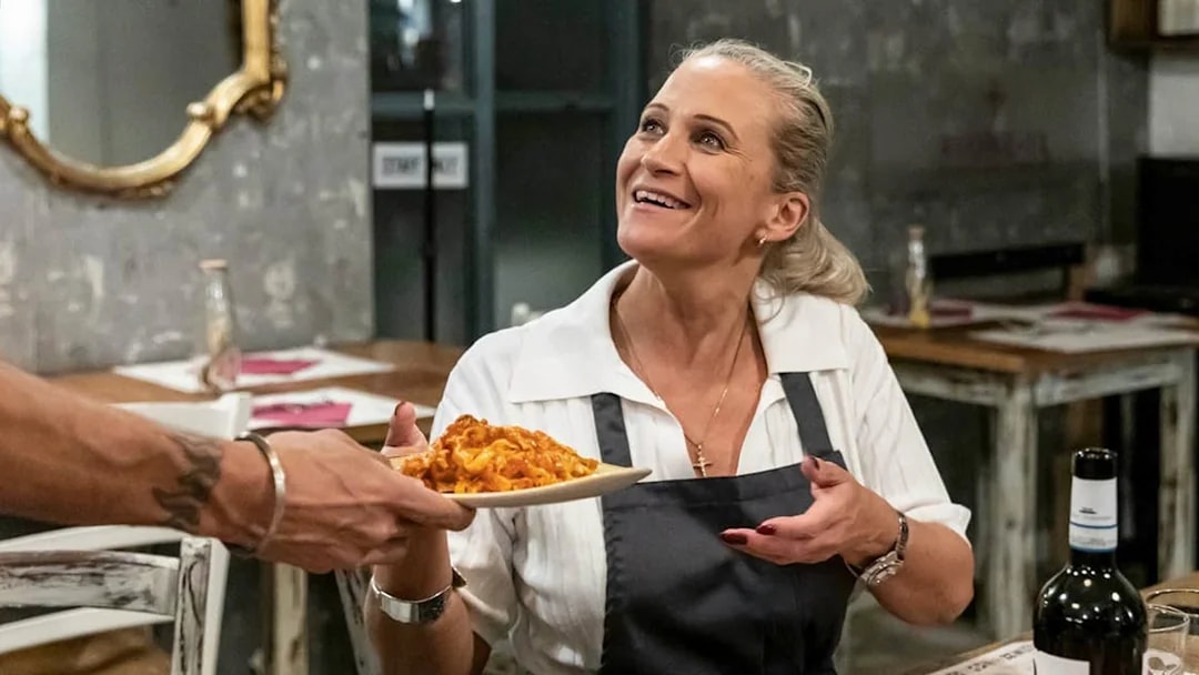 Woman receiving a plate of pasta during a cooking class in Trastevere, Rome.