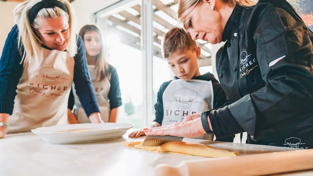 Fresh pasta making class with chef guiding participants in rolling dough.